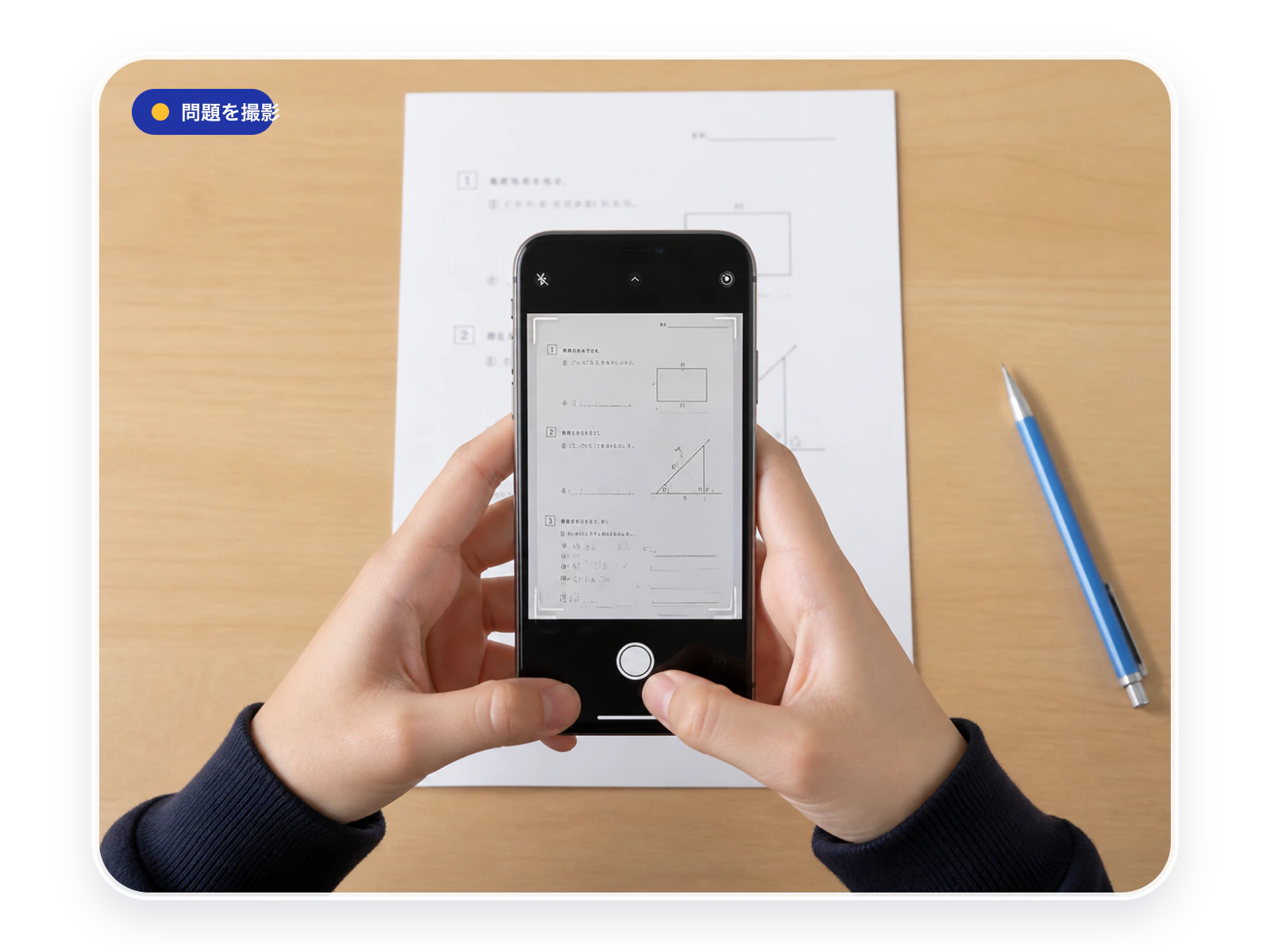 机の上の問題プリントをスマートフォンで撮影している様子